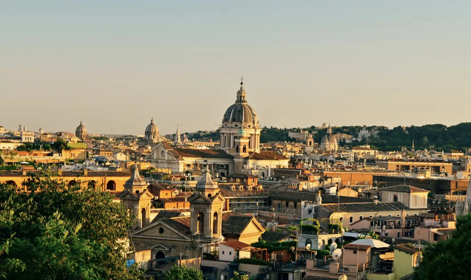 Panoramic sunset view of Rome skyline with prominent domes and terracotta rooftops