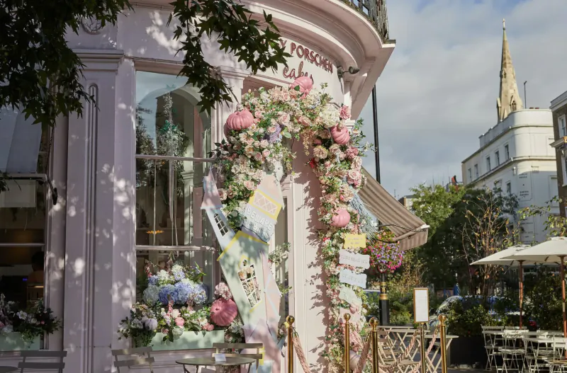 Pink boutique exterior at Eccleston Square Hotel London with floral arch, cafe tables, and church spire in background.