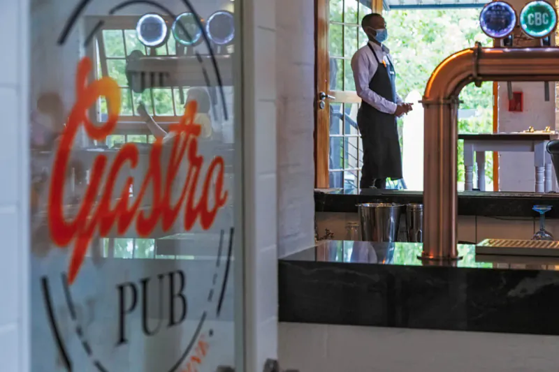 Castro Pub sign on glass door with masked bartender standing behind copper beer taps at the bar