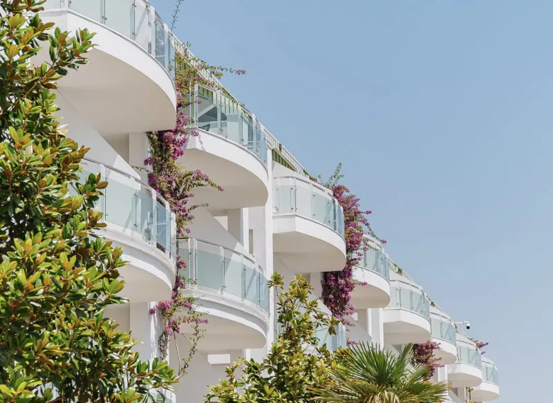 White curved balconies with purple bougainvillea and green plants at Corendon Playa Kemer luxury resort in Turkey