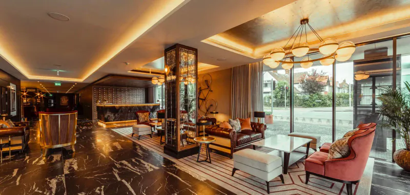 Luxurious lobby at The Fellows House Cambridge with marble floors, plush seating, reception desk, and large windows.