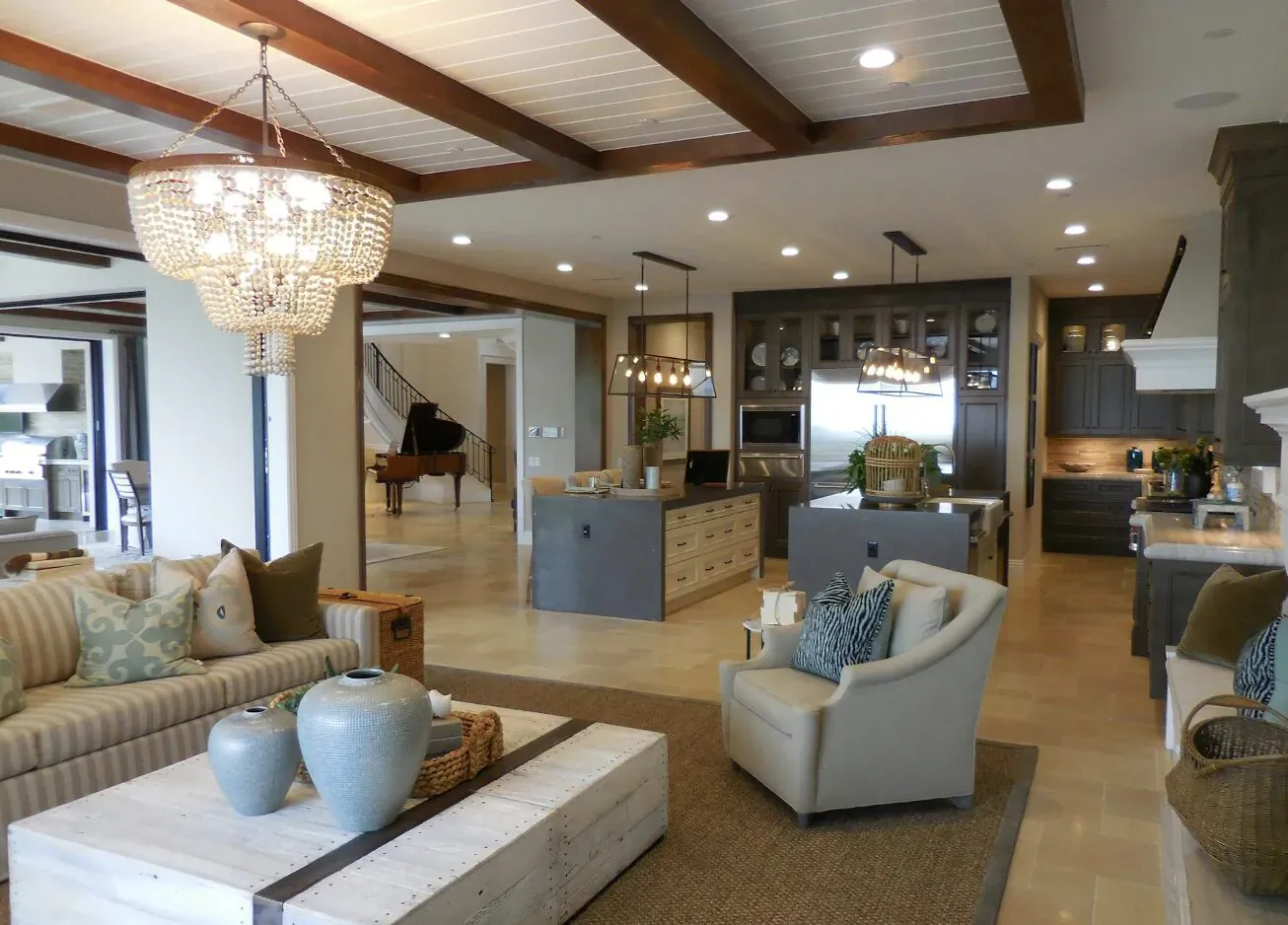 Luxurious open-plan living room and kitchen with chandelier, grand piano, white sofa, and modern cabinetry