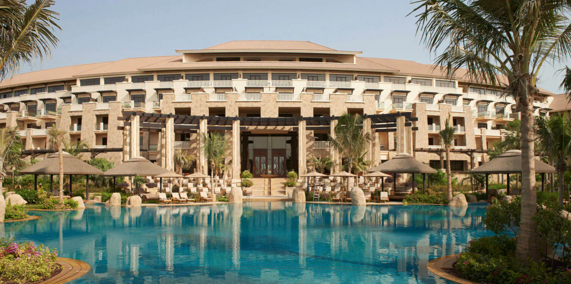 Sofitel Dubai the Palm resort: beige arched building with pool, palms, loungers, and Forbes Travel Guide 2022 recognition.