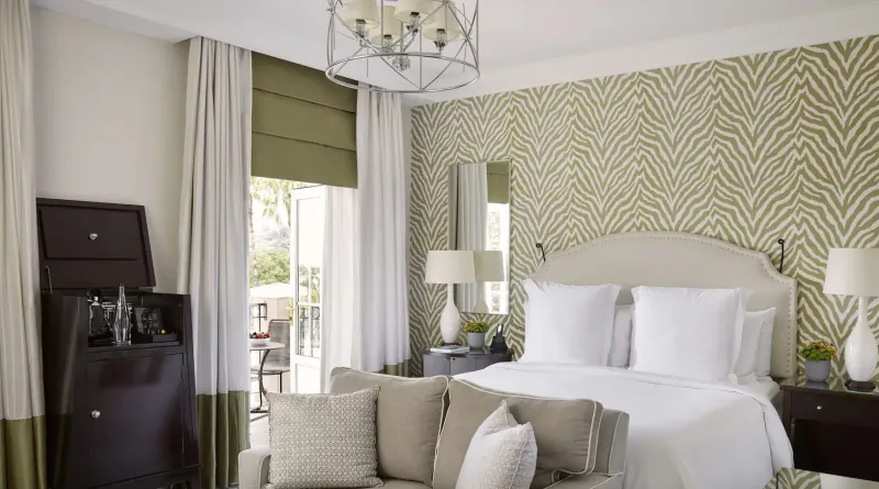 Elegant Four Seasons Westcliff hotel room above Johannesburg with king bed, zebra-print walls, balcony view, lamps, and bar cabinet.