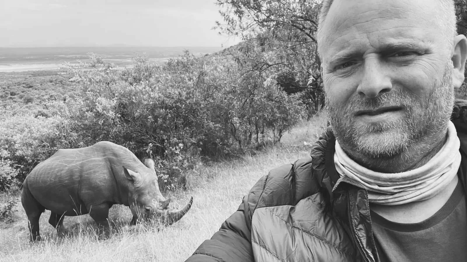 Wildlife photographer Johan Siggesson smiles with black rhino in African savanna, black and white selfie.