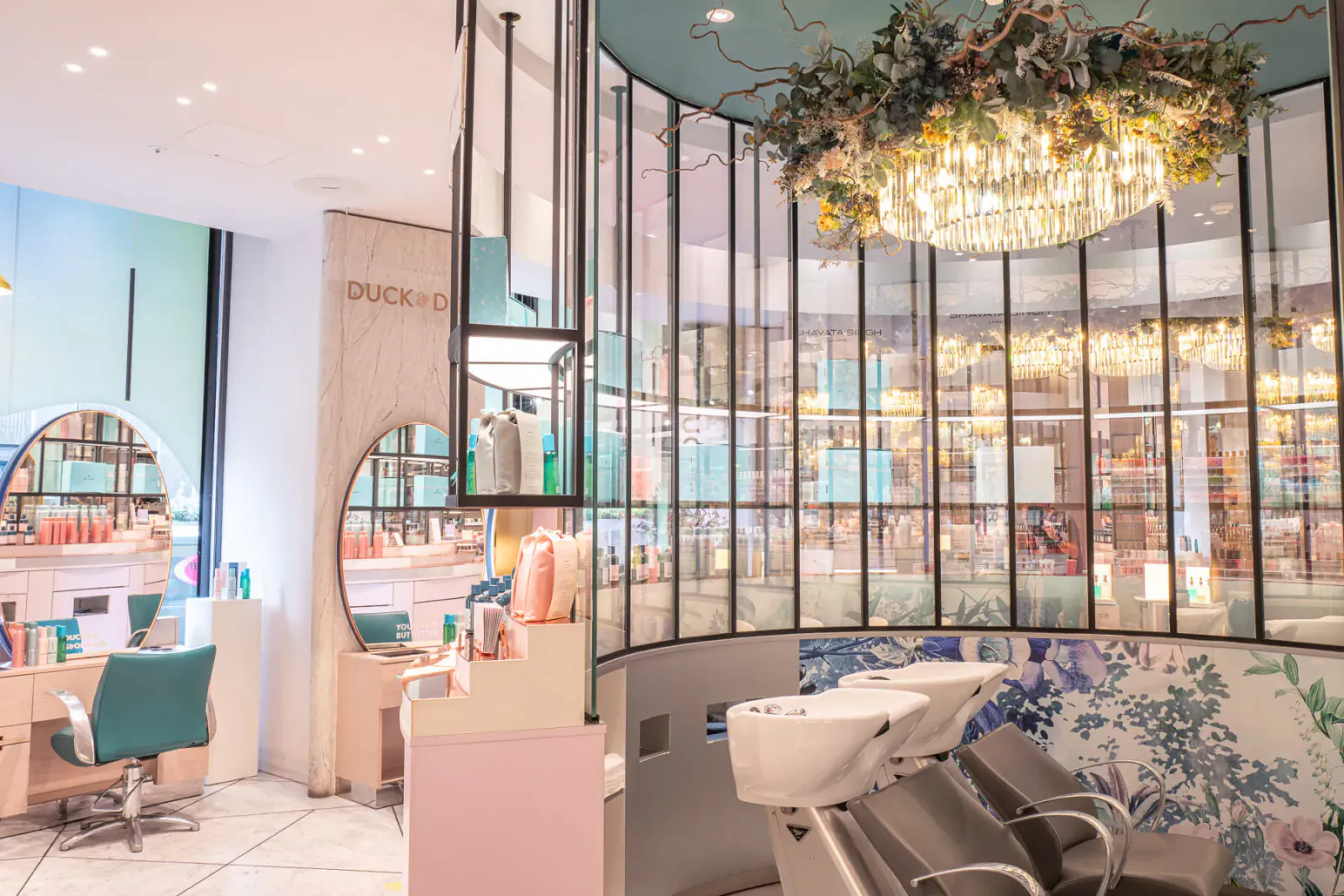 Luxurious Duck hair salon interior with pastel decor, mirrors, products, floral chandelier, and sinks