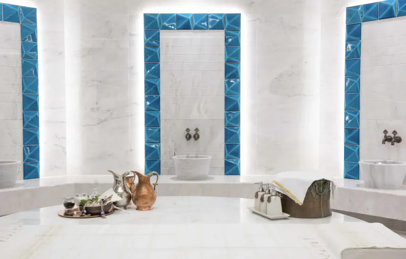 Luxurious Turkish hammam at Naturelife Spa with white marble, blue tiled walls, faucets, and brass tray on central table