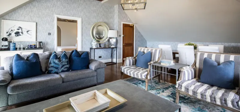 Elegant attic lounge at St. Brelade’s Bay Hotel with blue velvet sofa, armchairs, coffee table, and chandelier.