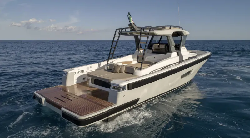 White luxury speedboat with teak deck and seating speeding rear view on open sea under blue sky.