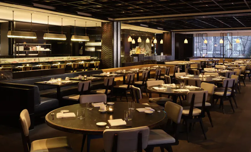 Elegant Nobu restaurant interior with dark wood tables, modern pendant lights, and large windows in Marylebone.