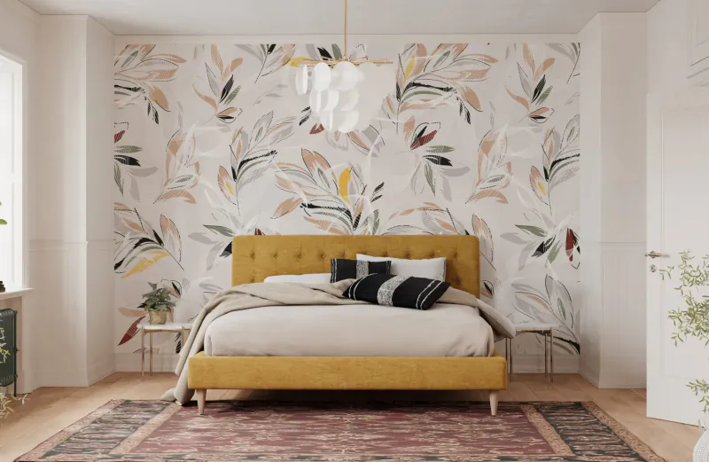 Cozy bedroom with mustard yellow upholstered bed, black-and-white pillows, floral wallpaper, plants, and pink rug.