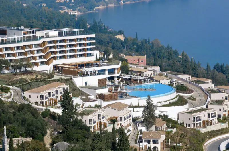 Aerial view of Angsana Corfu Resort and Spa on a hillside overlooking the sea with infinity pools.
