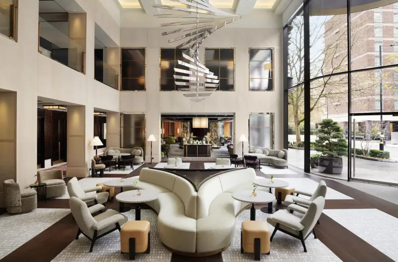 Spacious Nobu Hotel lobby in Marylebone with curved white sofas, modern pendant lights, bar, and glass walls overlooking bonsai tree.