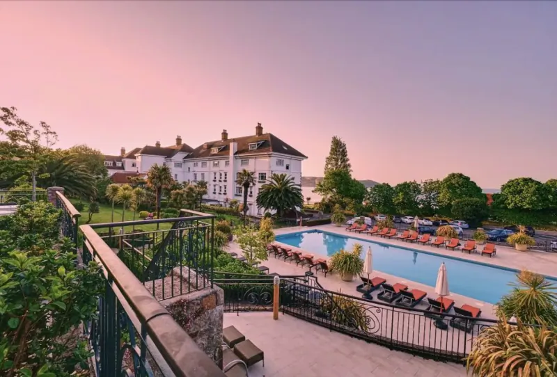 St. Brelade’s Bay Hotel in Jersey at sunset, with infinity pool, loungers, gardens, and bay view