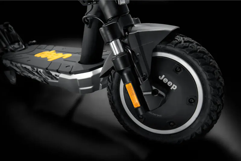Close-up of black Jeep electric scooter with yellow 'Jeep' logos on deck and wheel.
