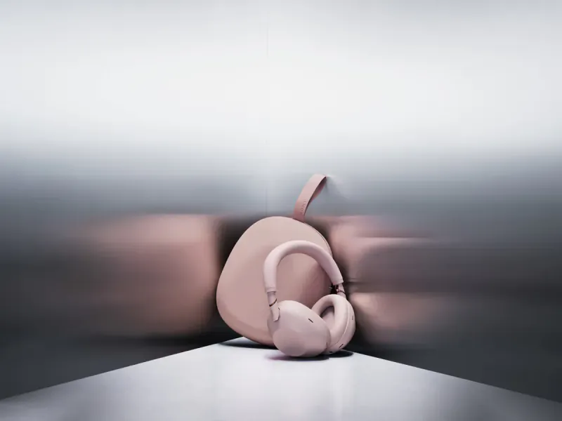 Pink Sony WF-1000XM6 wireless earbuds with case on reflective surface, blurred metallic background