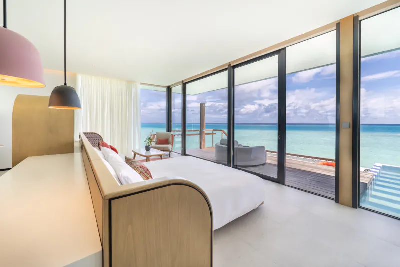 Modern SO/ Maldives overwater villa bedroom with ocean views, infinity pool, and plush bed.
