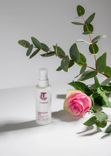 Thirns spray bottle with pink rose and eucalyptus leaves on white background