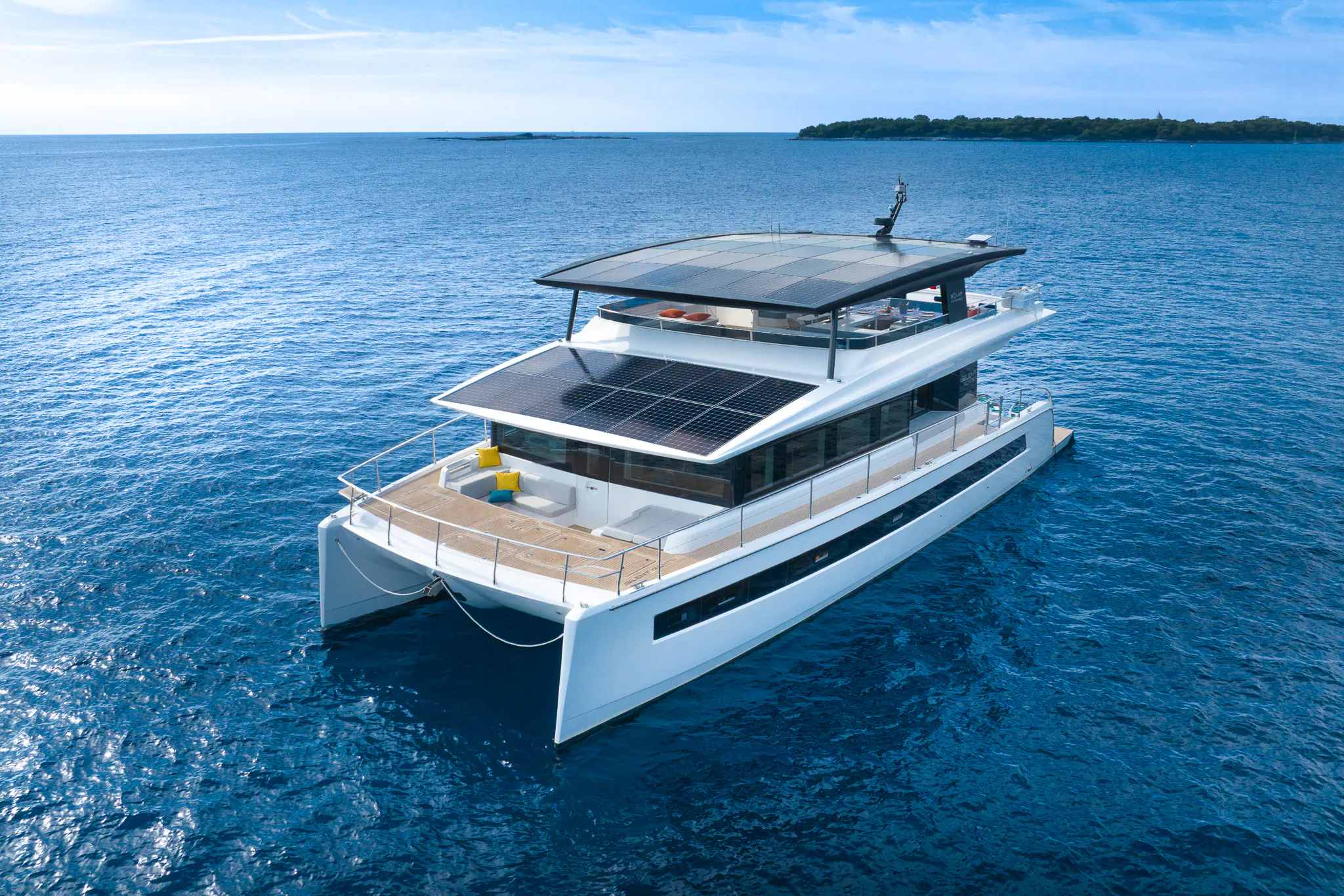 Aerial view of Silent Grace solar-powered catamaran yacht sailing on blue ocean under clear sky.