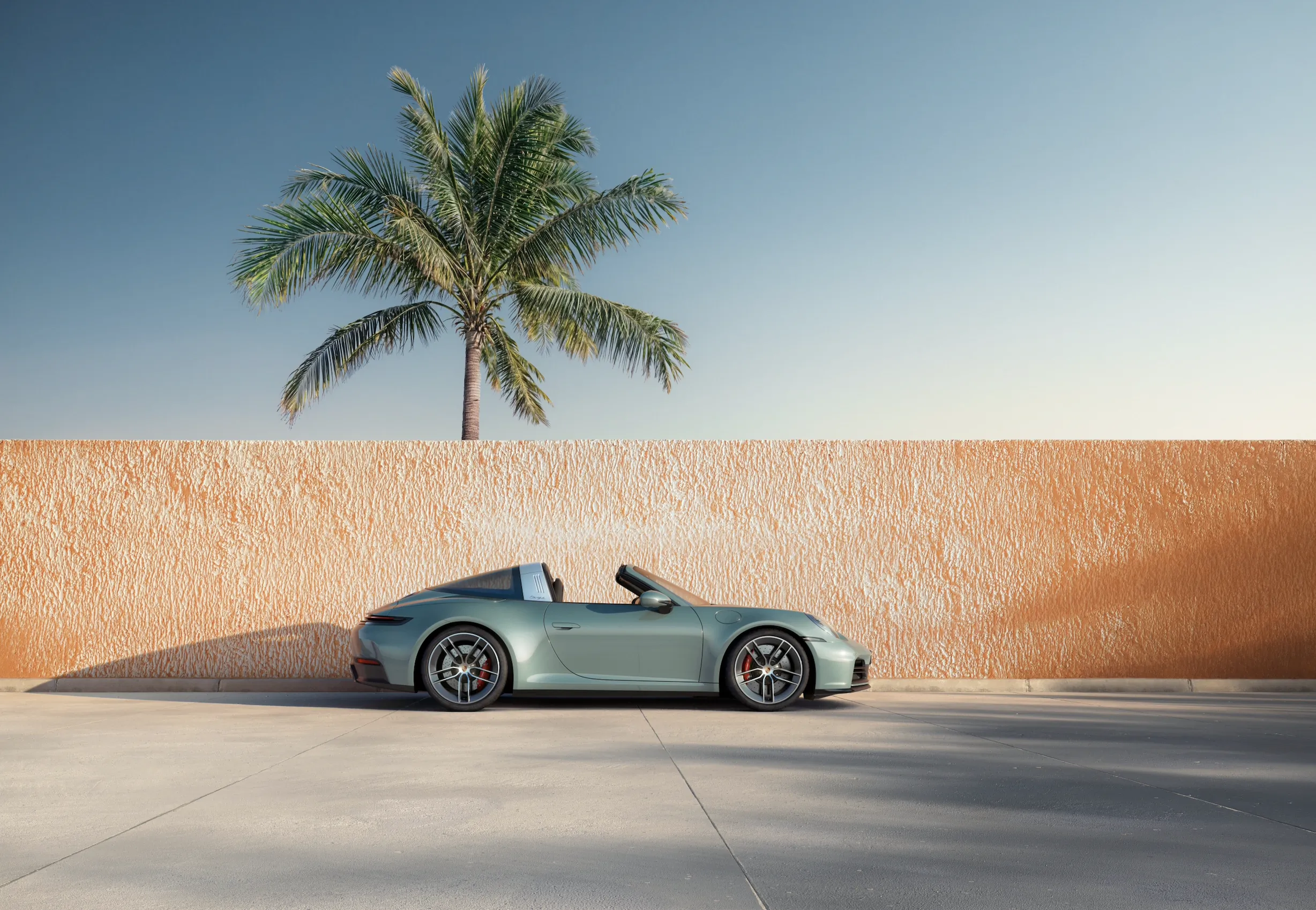 Teal Porsche 718 Boxster Spyder convertible parked beside orange wall with palm tree, tropical sunset vibe.