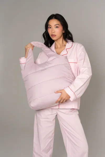 Asian woman in pink pyjamas holding large puffy mauve Kapten & Son Cloud Club tote bag