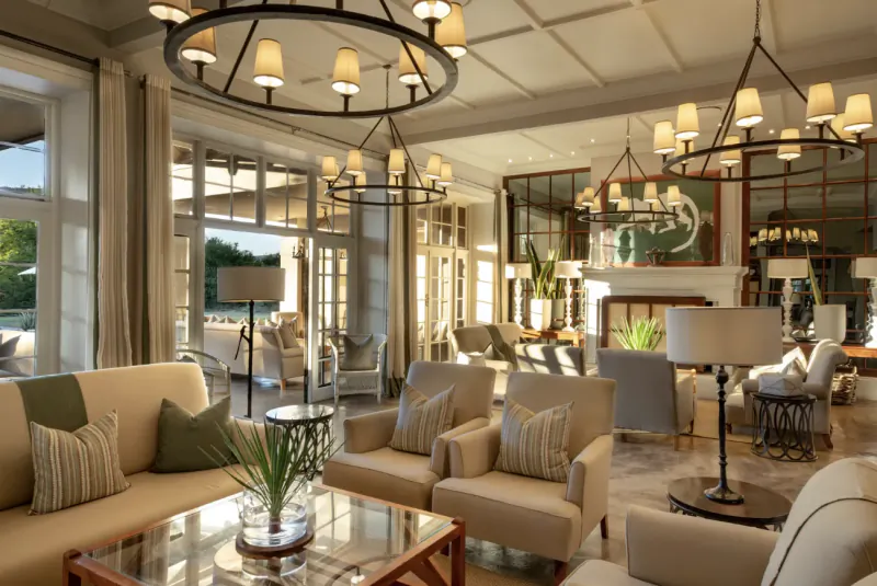 Elegant living room in Samara Karoo Safari Villa with cream sofas, glass coffee table, pendant lights, and pool view.