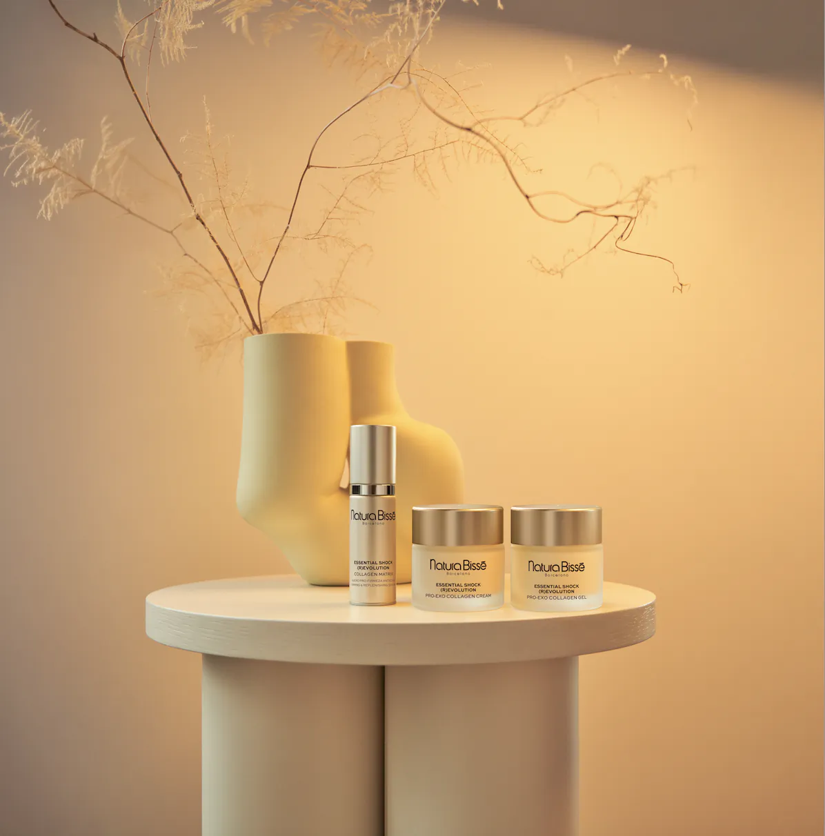 Natura Bissé skincare products on white table: Inhibit cream, jars with pampas grass, soft lighting