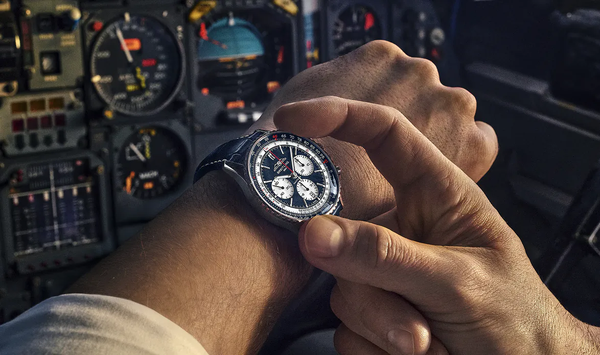 Breitling Tribute to Concorde chronograph watch on pilot's wrist in cockpit, hand adjusting it.