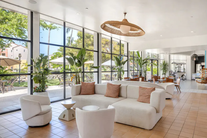 Bright Wyndham Puerto Rico Resort lobby with white sofas, plants, large windows, palm views, and woven chandelier.