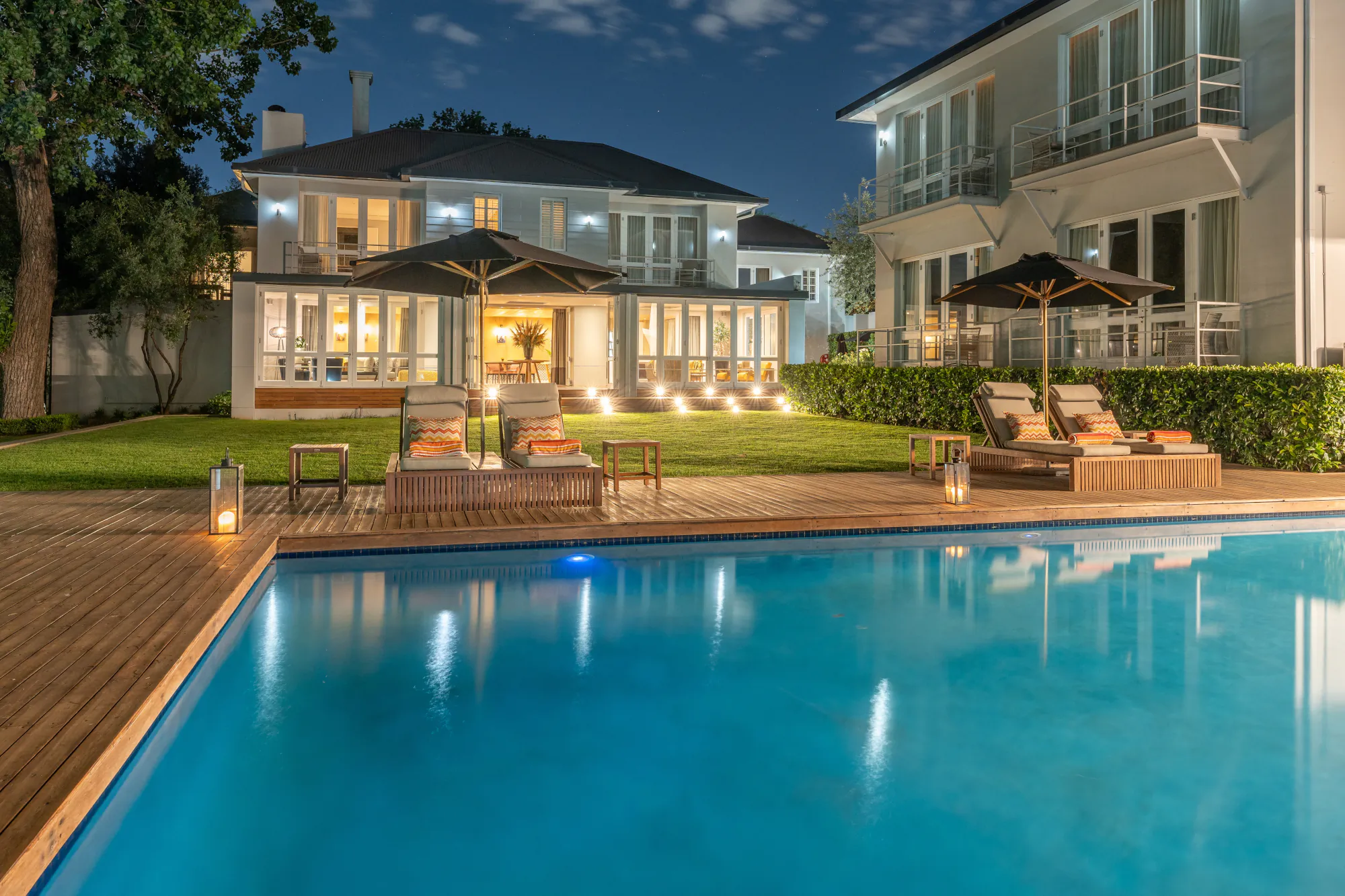 Night view of AtholPlace luxury villa with lit pool, loungers, umbrellas, and garden in Johannesburg