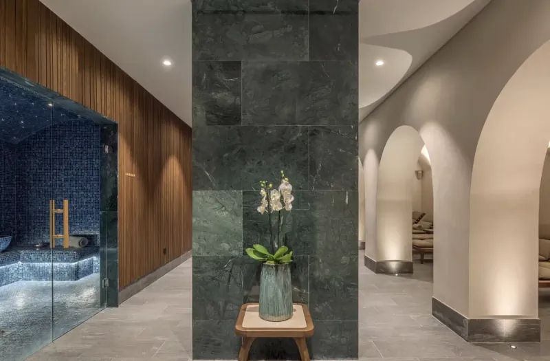 Luxury hotel spa with mosaic steam room, green marble pillar with white orchid, and arched lounge area