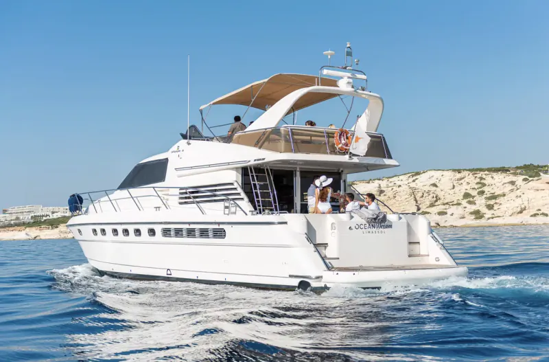 White luxury motor yacht 'OCEAN' cruising on blue sea near rocky Akamas coast with passengers on deck