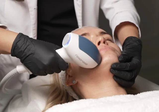 Practitioner in black gloves applying Resonate device to woman's face during skin treatment