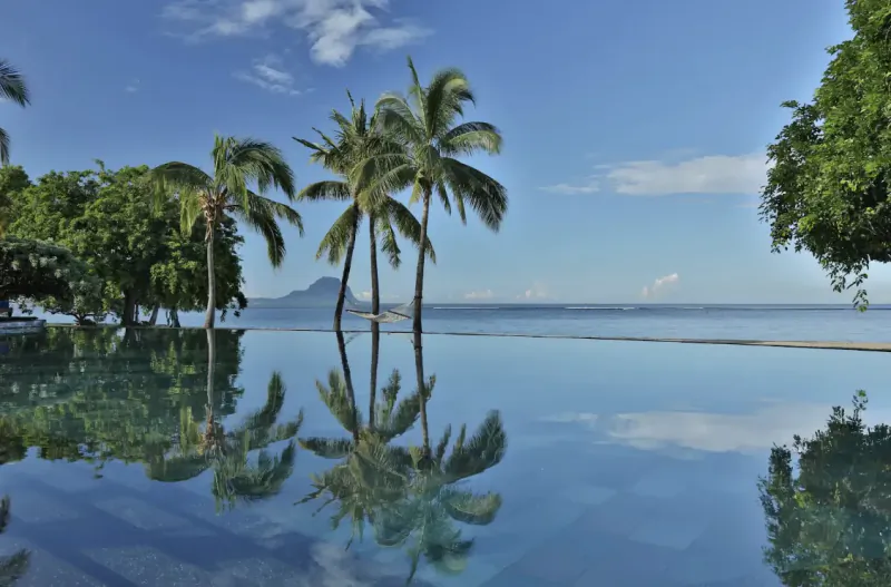 Infinity pool reflecting palm trees and ocean view at Maradiva Villas Resort in Mauritius