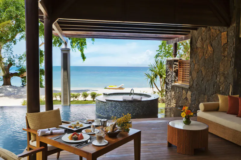 Luxury beachfront dining table with ocean view, outdoor hot tub, and lounge area at a Mauritius resort