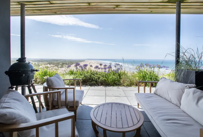 Patio with wooden furniture overlooking Saunton Sands beach and ocean under a pergola