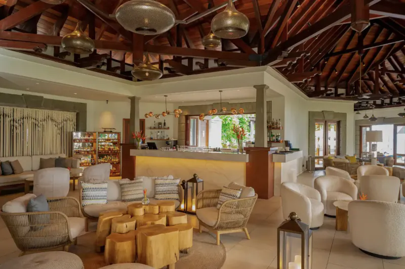 Elegant resort lobby lounge with wooden ceiling, pendant lights, bar, and cozy seating areas