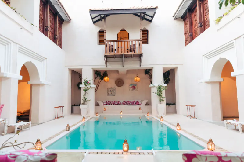 Courtyard pool at The Fort Shela Kenya villa with lanterns, seating, and upper balcony
