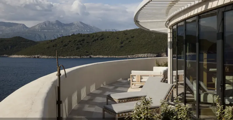 Luxury yacht deck with lounge chairs overlooking calm blue water and green mountains