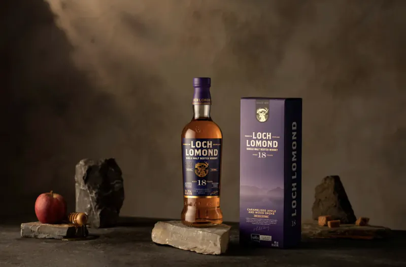 Loch Lomond 18 Year Old single malt whisky bottle and box on stone with apple and honey dipper