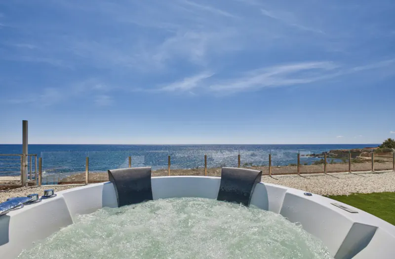 White hot tub with bubbling water overlooking the sea and blue sky