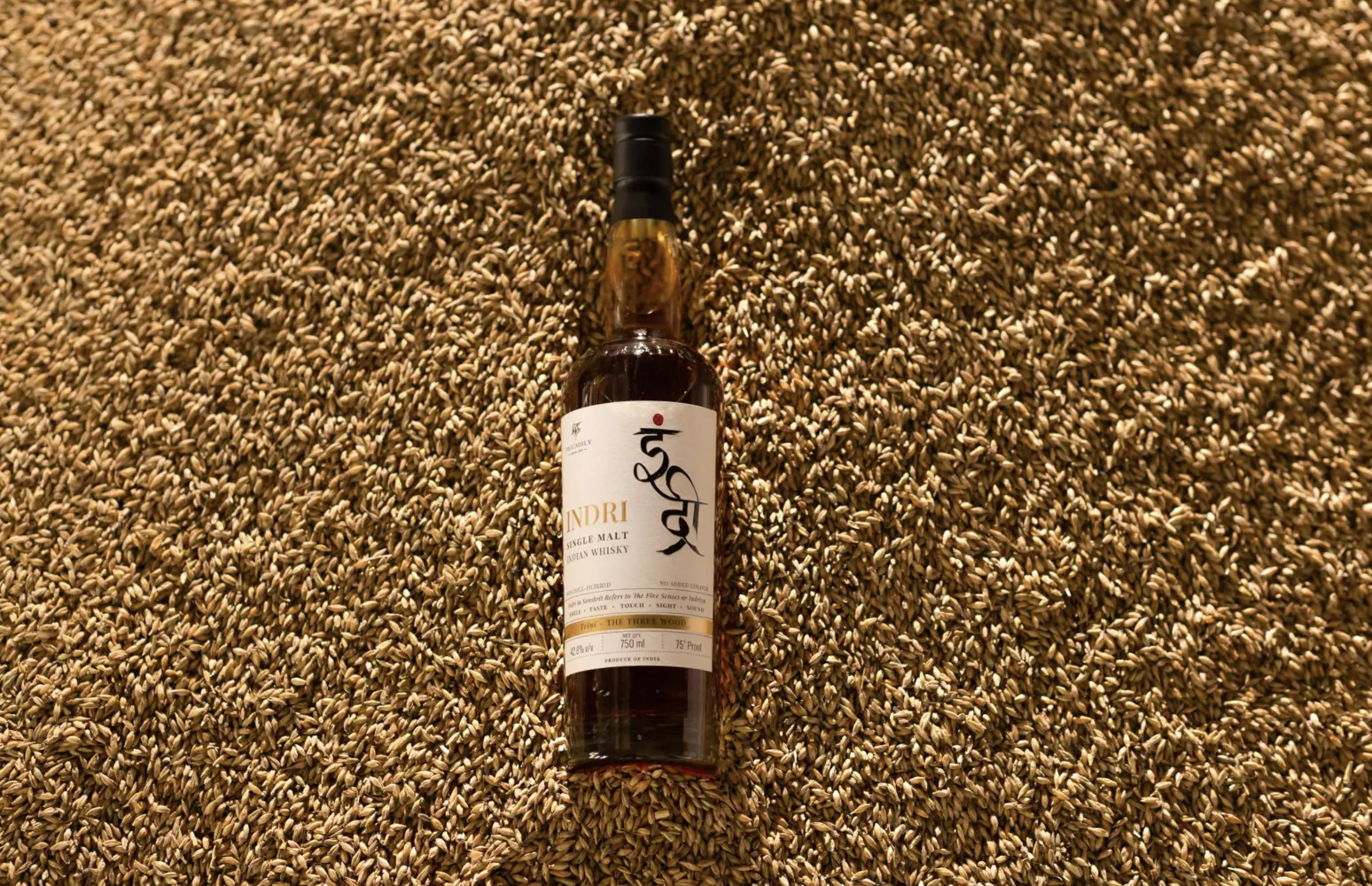 Indri single malt whisky bottle standing upright on a textured brown carpet