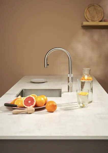 Modern kitchen sink with chrome Quooker boiling water tap, citrus fruits on plate, and glass carafe of infused water