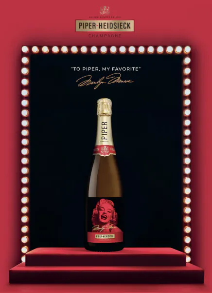 Piper-Heidsieck champagne bottle with Marilyn Monroe label on red stage with lights, quote 'To Piper, my favorite' by Marilyn Monroe