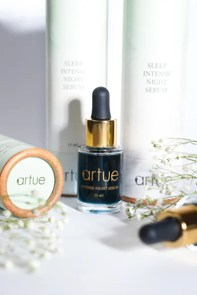 Artue Intense Night Serum dropper bottle with matching skincare products and white flowers