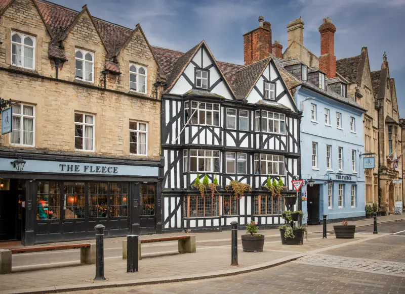 The Fleece historic pub with black-and-white timber facade and blue building beside it on a UK high street
