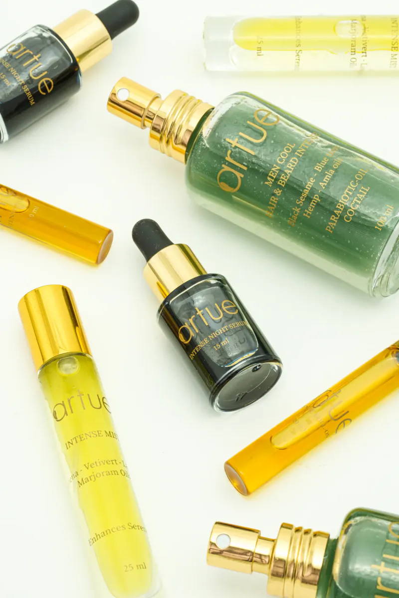 Assorted Artnue perfume oil bottles in black and green with gold caps on white background
