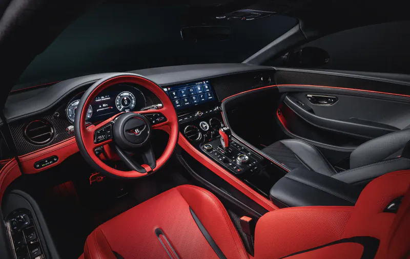 Luxury car interior with red leather seats, red steering wheel, and black dashboard with carbon fiber trim