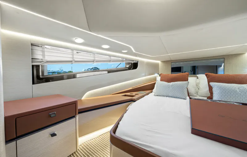 Luxury yacht cabin with large bed, orange pillows, and a window overlooking the sea