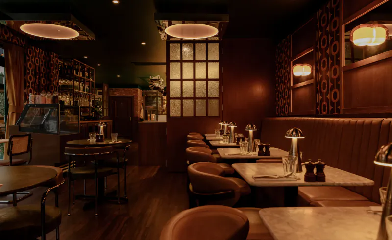 Warmly lit Italian restaurant interior with leather booths, marble tables, and patterned wall panels